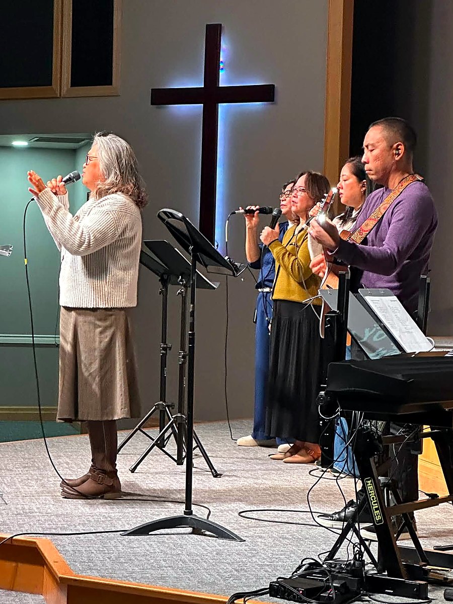 The MFBC worship team leading songs on stage beneath the cross